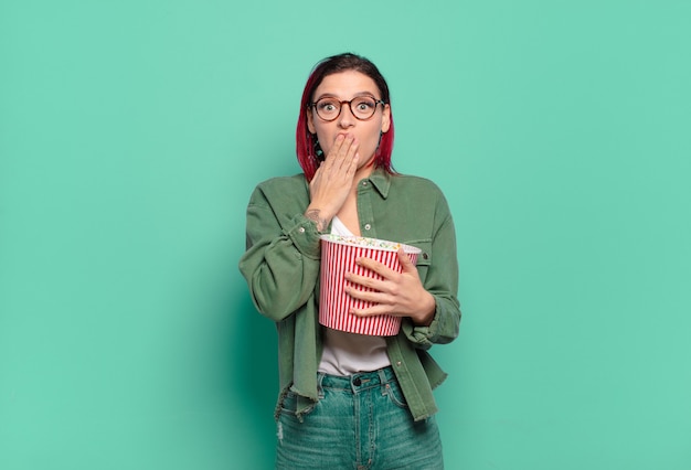 Bella donna dai capelli rossi con popcorn e telecomando per la tv