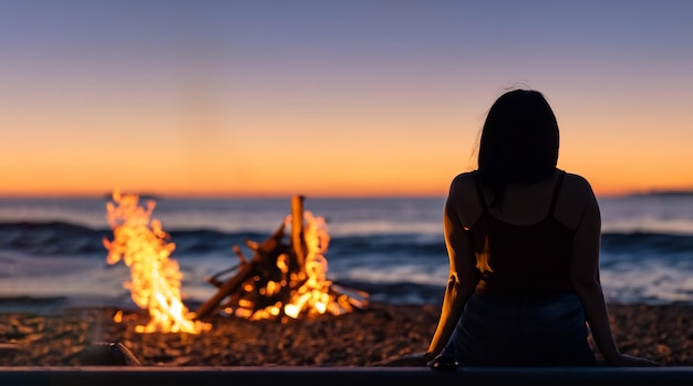 Bella donna dal retro con un falò su una spiaggia