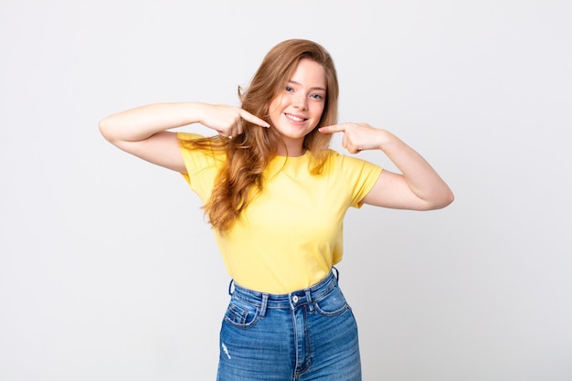 Bella donna dalla testa rossa che sorride con sicurezza indicando il proprio ampio sorriso