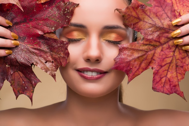 Bella donna dentro con le foglie asciutte di autunno