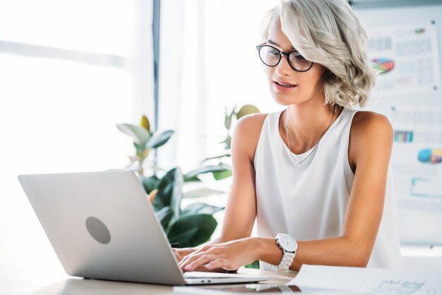 Bella donna di affari caucasica che utilizza computer portatile in ufficio