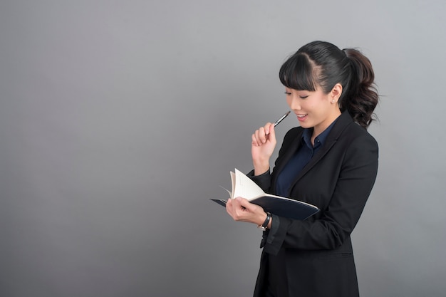 Bella donna di affari che pensa su fondo grigio