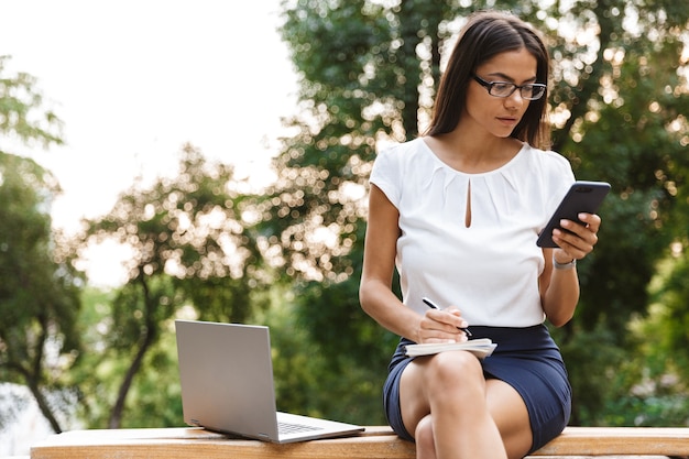 Bella donna di affari scrivere note in chat dal telefono cellulare