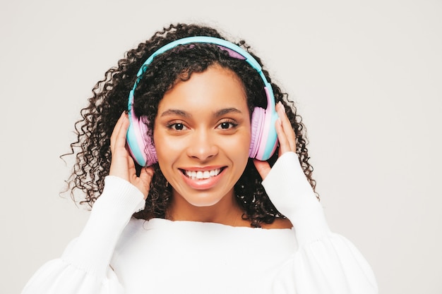 Bella donna di colore con l'acconciatura di riccioli afro. Modello sorridente in maglione e jeans