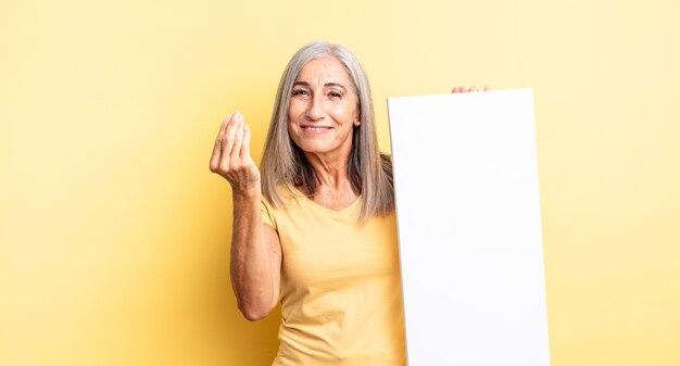 Bella donna di mezza età che fa un gesto di capice o denaro, dicendoti di pagare. concetto di tela vuota