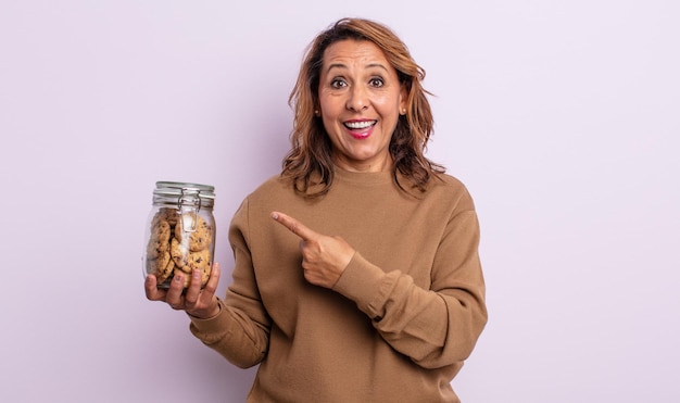 Bella donna di mezza età che sembra eccitata e sorpresa che indica il concetto di biscotti fatti in casa laterali