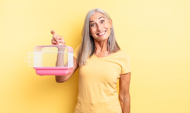 Bella donna di mezza età che sembra felice e piacevolmente sorpresa. gabbia per animali domestici o concetto di prigione