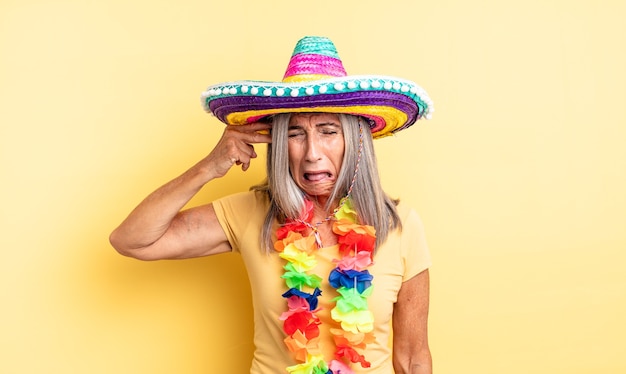 Bella donna di mezza età che sembra infelice e stressata, gesto suicida che fa il segno della pistola. concetto di festa messicana