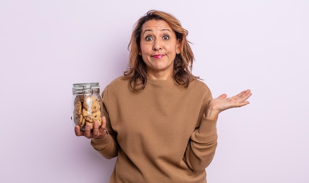 Bella donna di mezza età che si sente perplessa, confusa e dubita. concetto di biscotti fatti in casa