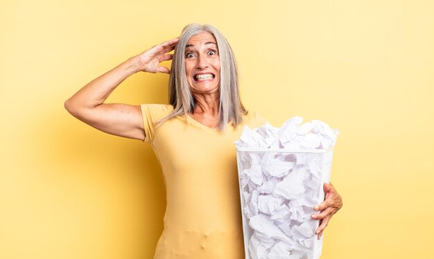 Bella donna di mezza età che si sente stressata, ansiosa o spaventata, con le mani sulla testa. concetto di fallimento delle palle di carta