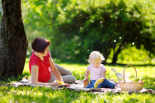 Bella donna di mezza età e il suo adorabile nipotino avendo un picnic nel parco soleggiato