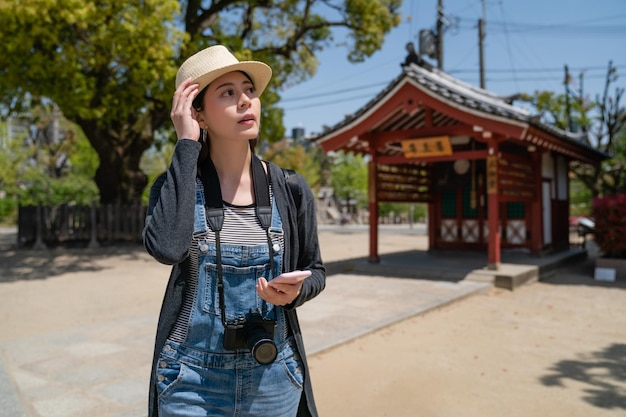 bella donna di viaggio che cerca per telefono e si guarda intorno per trovare qualcosa nel tempio.