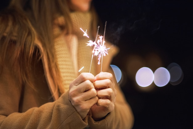 Bella donna divertendosi, con lo sparkler in sue mani che celebrano la vigilia del nuovo anno