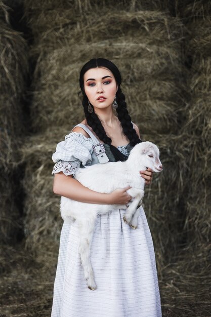 bella donna è in piedi sul fienile con una capra bambino