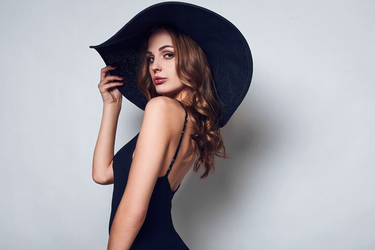 Bella donna elegante con un vestito nero e un cappello
