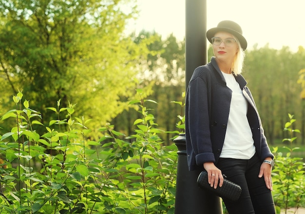 Bella donna elegante in piedi in un parco in autunno