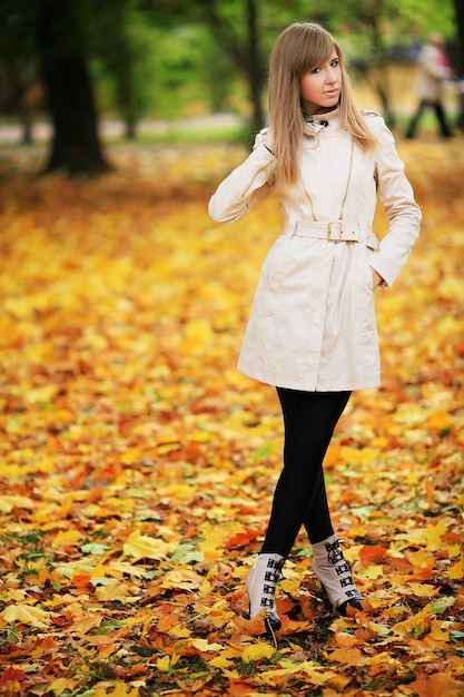 Bella donna elegante in piedi in un parco in autunno