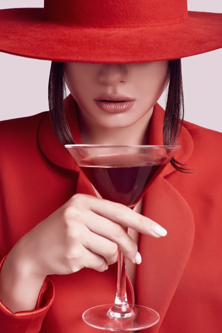 Bella donna elegante in un vestito alla moda rosso e cappello con cocktail