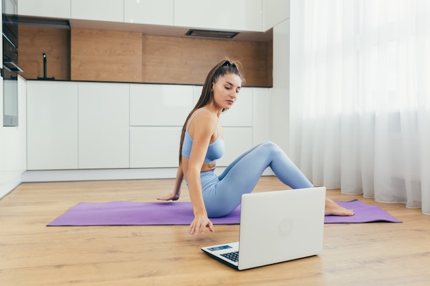 bella donna facendo fitness a casa in linea con il computer portatile