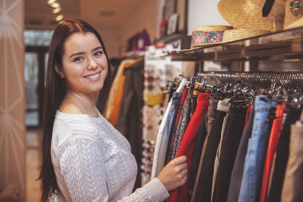 Bella donna felice che gode della compera al negozio di vestiti