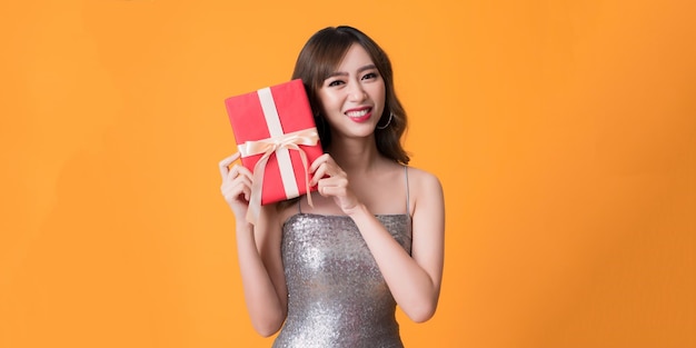 Bella donna felice che indossa un vestito luccicante con una scatola regalo alla festa