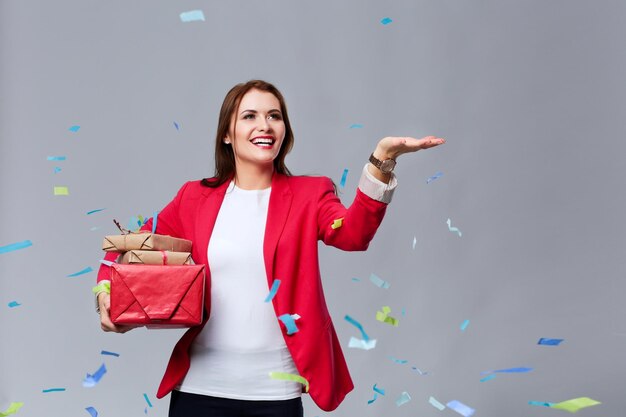 Bella donna felice con confezione regalo alla festa con coriandoli Compleanno o Capodanno che celebra il concetto