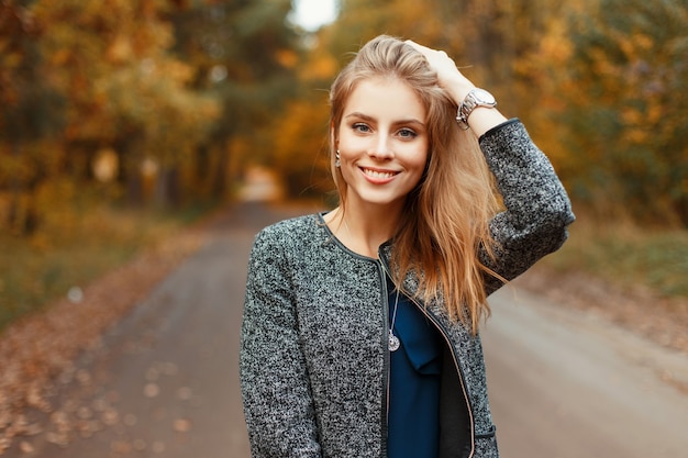 Bella donna felice con un sorriso in un cappotto alla moda autunno in posa nel parco
