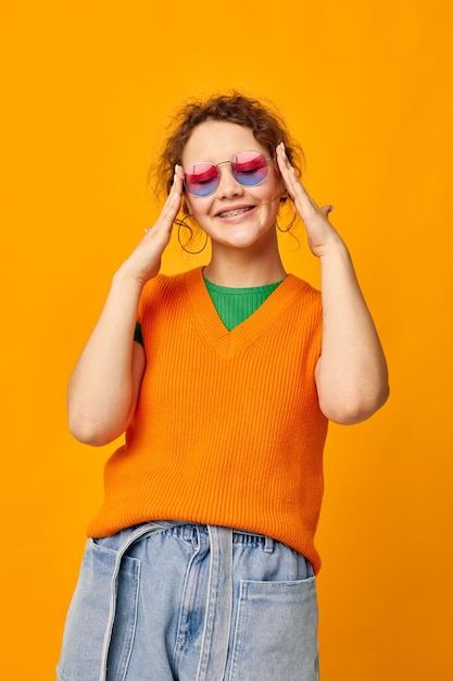 Bella donna felpe arancioni occhiali da sole occhiali multicolori fornitura sfondo giallo inalterato