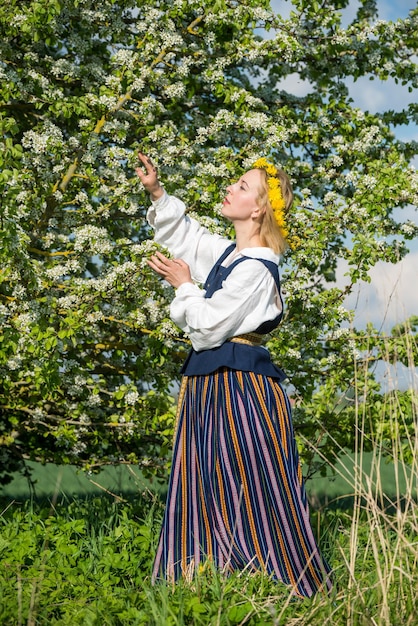 Bella donna femminile in abito nazionale con fiori primaverili bianchi