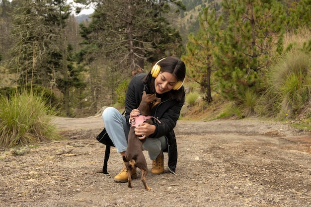 Bella donna gioca con il suo cane nella foresta in una giornata nuvolosa