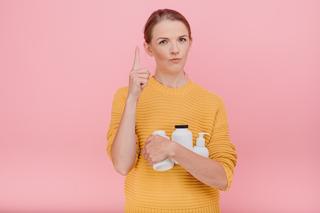 Bella donna graziosa che tiene in mano una bottiglia di pillole mediche o vitamine vestita casualmente