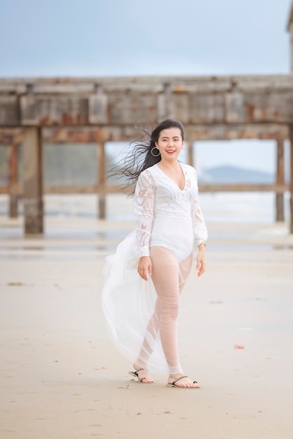 Bella donna in abito bianco che passeggia felicemente in spiaggia