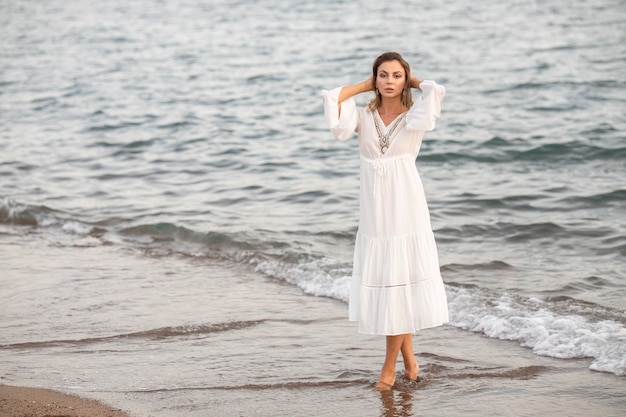 Bella donna in abito bianco in riva al mare