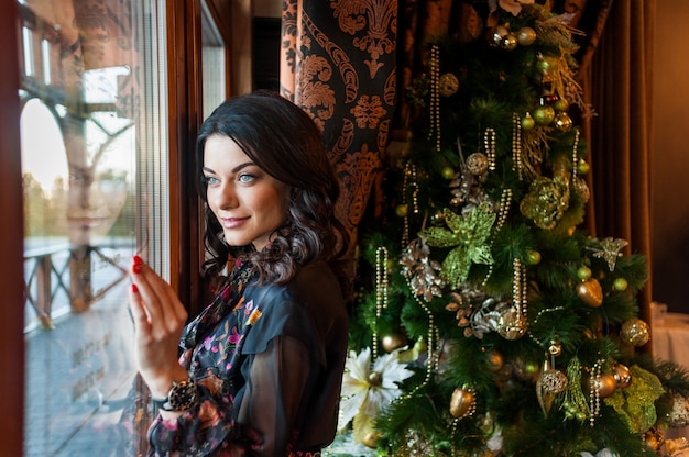 Bella donna in abito da sera vicino all'albero di Natale