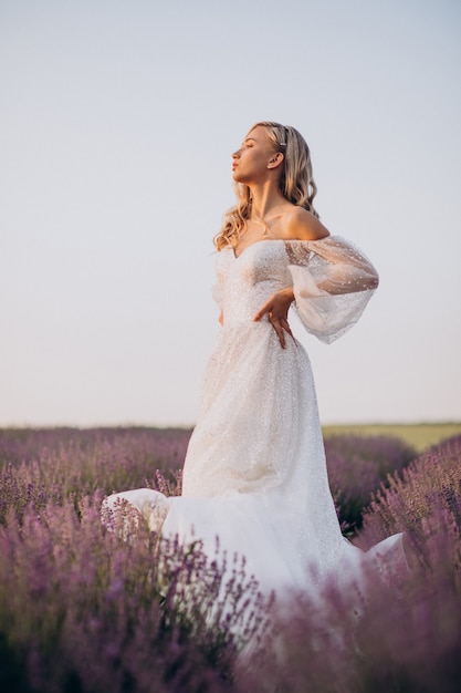 Bella donna in abito da sposa in campo di lavanda