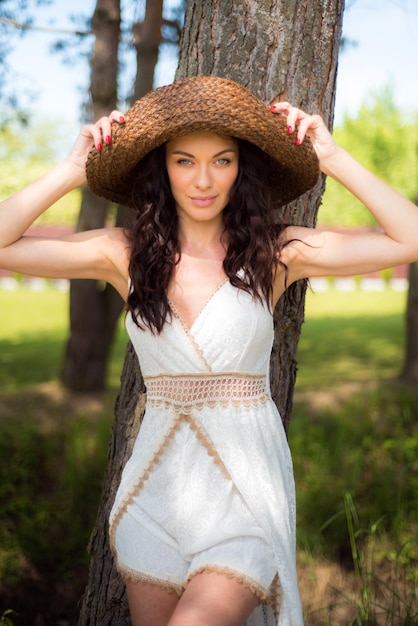 Bella donna in abito estivo bianco e cappello di paglia in giardino