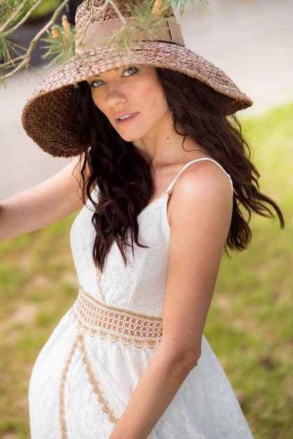 Bella donna in abito estivo bianco e cappello di paglia