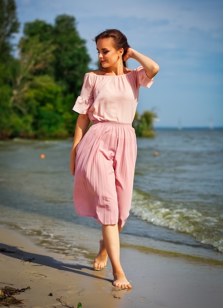 Bella donna in abito lungo sulla spiaggia
