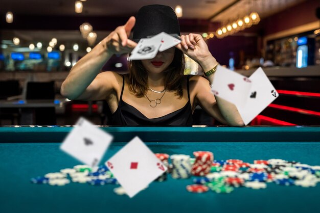 Bella donna in abito nero da sera gioca a poker nel casinò