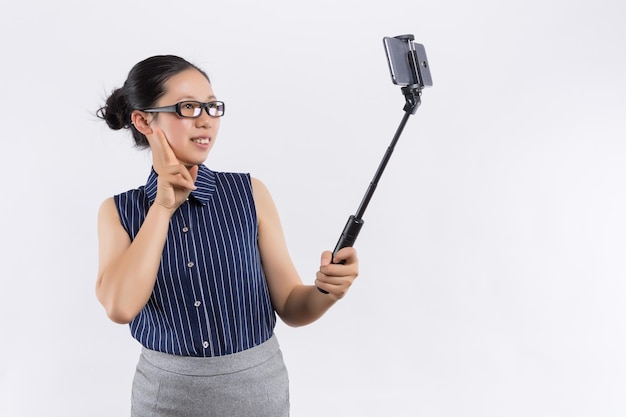 Bella donna in abito rosso con viso carino perfetto e occhi azzurri prendendo selfie con smartphone in studio