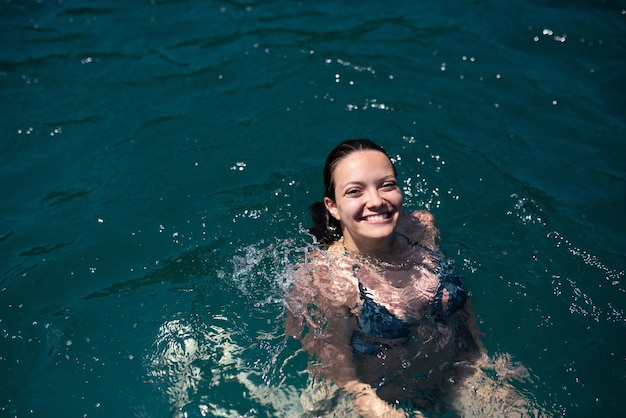 Bella donna in bikini verde sulla spiaggia tropicale Ritratto di giovane donna felice sorridente in mare Ragazza bruna abbronzata in costume da bagno godendo sulla spiaggia