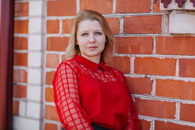 bella donna in camicia rossa. rughe sul viso della donna. bionda in una camicetta rossa. una bella mamma