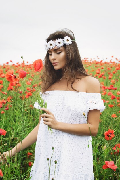 Bella donna in campo con molti fiori di papavero