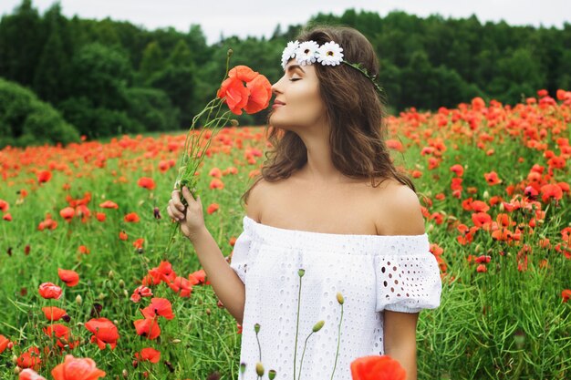 Bella donna in campo con molti fiori di papavero