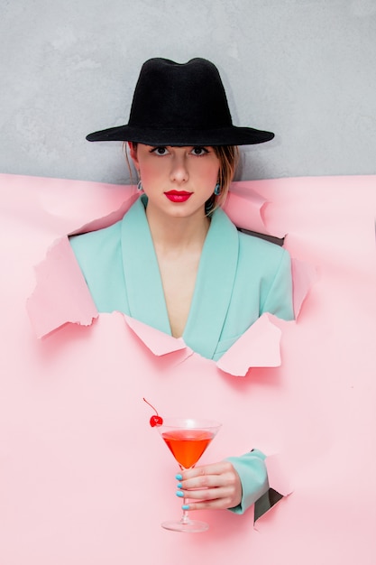 Bella donna in cappello e giacca classica blu con bicchiere da martini