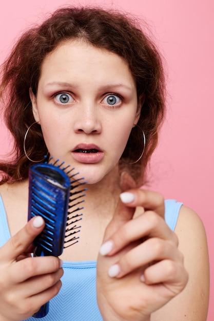 Bella donna in magliette blu pettina con capelli emozioni colore rosa sfondo