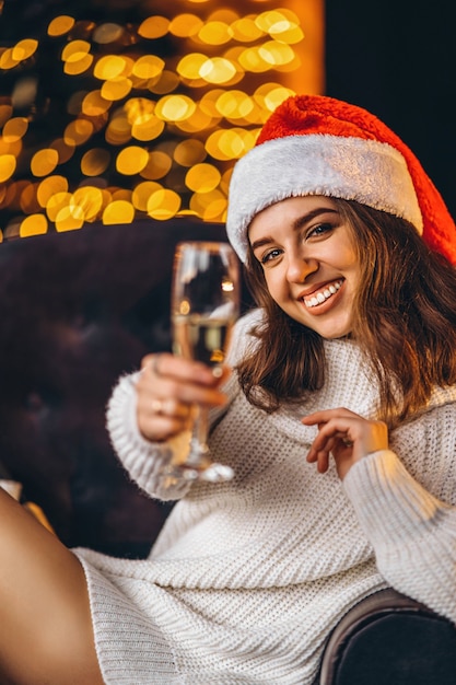 Bella donna in maglione caldo, calzini e cappello di Natale, seduta sul pavimento