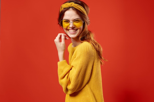 Bella donna in maglione giallo occhiali moda emozioni sfondo rosso