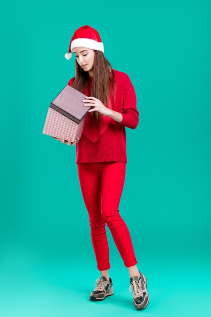 bella donna in maglione rosso e cappello di natale con confezione regalo su sfondo verde