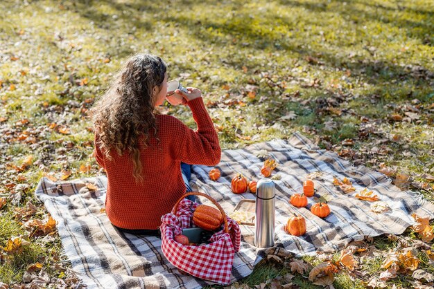 Bella donna in maglione rosso su un picnic in una foresta d'autunno